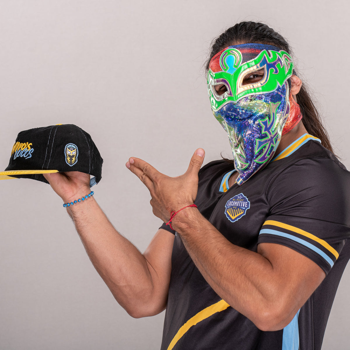 Bandido wearing his El Paso Locomotive jersey and holding the collaboration hat
